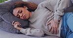 Person, sick and period pain on home sofa with endometriosis, colon crisis and ibs constipation. Biracial woman, stomach ache or stress from tummy virus, gut health risk and gastrointestinal bloating