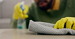 Closeup hands, person and spray bottle for cleaning table in house living room for virus safety, bacteria and furniture dirt. Fabric, cloth and liquid chemical product for desk in home housekeeping