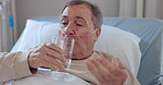 Water, medicine and a senior man in the hospital for healthcare, treatment or recovery in bed. Glass, pills and medical with an elderly patient on an IV drip in a clinic for chronic medication