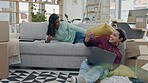 Pillow fight, new home and couple on sofa, smile and bonding in living room, apartment or property. Happy, man and woman play with cushion on moving day, real estate and energy in interracial house