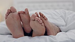 Couple, feet and play in bedroom in home, relax in peace and rest in blanket in the morning together. Barefoot, bed and man and woman rubbing in sleep for comfort, bonding and care for love in house