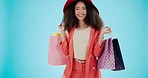 Fashion, shopping bag and spin with face of woman in studio for boutique, retail and wardrobe. Product, choice and luxury with portrait of customer on blue background for promotion, gift and sales