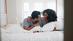 Hug, conversation and couple in bed, funny and bonding together in home to laugh. Embrace, interracial love and man and woman smile in bedroom talking, healthy connection and relax in the morning