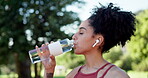 Exercise, drinking water and music outdoor for running, fitness and workout at a park. Bottle, listening to podcast and athlete woman runner in nature to start cardio, sports or training for wellness