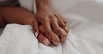 Love, intimacy and couple holding hands in bed for intimacy, care and affection at home in morning. Healthy relationship, marriage and people in bedroom laying together for bonding, relax and embrace