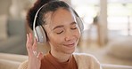 Young woman, headphones and listening on sofa in home for music, sound or happy for memory, idea or vision. Girl, smile and thinking with audio streaming subscription, choice or click on lounge couch