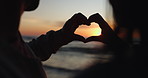 Silhouette, sunset and hands of couple with heart shape at the beach as love on holiday or tropical vacation together. Ocean, sign and people with care, support or trust symbol for hope on an island