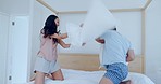 Happy couple, bed and playing in pillow fight, bonding or fun holiday weekend together at home. Excited man and woman smile in happiness enjoying playful game with cushion in bedroom at the house