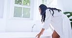 Woman, cleaning and running water in a bath to relax in the morning while on holiday or vacation. Bathroom, stress relief and aromatherapy with a young female in a bathrobe for skincare or wellness