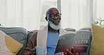 Coffee, mature black man and reading book in home on living room sofa. Happy, novel and African person drink tea in lounge to relax, study and knowledge of fantasy story in retirement hobby in house