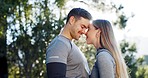 Fitness, kiss and couple in forest with love, romance and relax after hiking, running or workout in nature. Exercise, break and man with woman in park kissing, bond or relax in nature after training