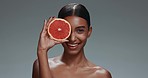 Woman, face and skincare with grapefruit, studio or shine with health, wellness or beauty by dark background. Girl, model and cosmetics with fruit, nutrition or glow with facial aesthetic in portrait