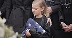 Funeral, cemetery and child with American flag for veteran for respect, ceremony and memorial service. Family, depression and sad girl by coffin in graveyard mourning military, army and soldier hero