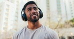 Man, thinking and music with headphones in city for a workout, exercise or training. Athlete person outdoor on break or rest with a happy smile, fitness and listening to audio for motivation on run
