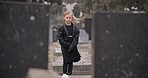 Sad, death or kid in cemetery for funeral. spiritual service or grave visit for respect in Christian religion. Mourning, tomb or depressed girl child outside in graveyard for grief, loss or farewell