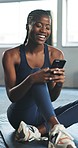 Gym, fitness and black woman with a smartphone, typing and funny with connection, social media and exercise. Person on the floor, happy and girl with a cellphone, mobile app and relax with workout