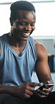 Funny, fitness and black man with a smartphone, typing and smile with workout, connection or relax. African person, health or guy with humor, mobile app or cellphone with social media, laugh or break