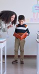 Boy, reading and book with presentation, classroom or oral assessment with teacher, development or language. Shy kid, story and speech with test, literature and education in class, school or academy