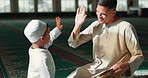 Muslim, high five in a mosque and a father with his son to study the quran for faith, belief or religion together. Family, kids and ramadan with a man teaching his boy child about islamic success