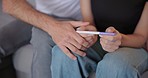 Closeup, hands and a couple with pregnancy test results, comfort and reading together. Family, support and a man and woman with information on a baby, pregnant and care on the sofa for infertility