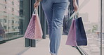 Shopping bags, walking and legs of woman in mall, shop and travel commute to luxury fashion store. Back, hands and gift of customer in boutique, retail market and sales discount on clothes of person
