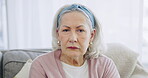 Sad, face and a senior woman on the sofa with depression, anxiety or mental health in a home. Illness, lonely and portrait of an elderly person on the couch with Alzheimer or lost in retirement