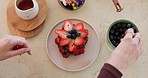 Hands, strawberry dessert and cooking on table, kitchen and chef with art, cuisine or floral pattern in top view. Woman, closeup and blueberry for flower shape, vegan meal or pancakes for fine dining
