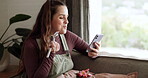 Eating breakfast, phone and happy woman in home on living room sofa. Smartphone, food and person on couch on social media, reading email and mobile app for nutrition, healthy diet and wellness fruits