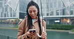 Phone, umbrella and woman in rain in a city typing on social media or search location on internet or app gps in morning. Winter, web and person on vacation or holiday and chatting with connection