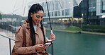 Phone, walking and woman in rain in a city typing on social media or search location on internet or app gps in morning. Winter, umbrella and person on vacation or holiday and chatting with connection