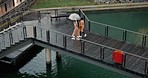 Walking, above and women in the rain on a boardwalk for relax, communication or on vacation. Travel, bridge and drone view of friends with an umbrella for security from water in winter on holiday