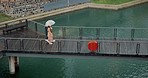 Walking, morning and women on bridge during rain for nature bonding, vacation or weekend together. Talking, above and friends or people with an umbrella in winter for shelter on a boardwalk by a lake