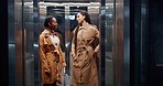 Elevator, business women and conversation in a office building at company going down. Female staff, happy and speaking of professional worker with a smile at hotel with workforce and job travel