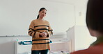 Education, university and a woman teacher in a class for learning, growth or development with a lesson. College, teaching and lecture with a young educator talking to students in an academy classroom