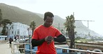 Fitness, check time and black man in city for performance, health tracking and mobile app. Sports, wellness and happy person by sea on smart watch for marathon training, exercise and runner workout