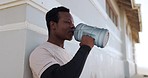 Black man, drinking water and relax in fitness on beach workout, exercise or outdoor training. Tired African male person on break, rest or mineral liquid for natural nutrition, diet or sustainability