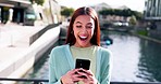Phone, wow and good news with a woman excited as a lottery winner while outside on a bridge across a river. Contact, surprise and notification with a happy young person reading an alert on her mobile