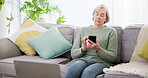 Phone, senior woman typing on sofa and relax in home living room, reading retirement email and internet news. Smartphone, scroll and elderly person on couch in lounge, social media and communication