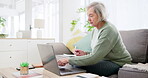 Laptop, writing and documents for finance with an old woman in the living room for retirement planning. Computer, accounting and investment for pension with a senior adult on a sofa in her home