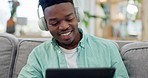 Man, headphones and music with tablet in home for audio, radio and relax with podcast on sofa. Happy young african guy, dance and listening to digital multimedia app, streaming sound or hearing song 