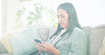 Phone, social media and a business asian woman on a sofa in the living room of her home for communication. Mobile, contact and networking with a young employee in her house after work to relax