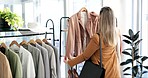 Woman, customer and fashion with clothing rack in shopping, sale or discount at boutique store. Female person or shopper checking line of clothes in fabric, material or retail shop at the indoor mall