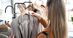 Woman, customer and fashion with clothing rack in boutique store for shopping, sale or discount. Female person or shopper checking line of clothes in fabric, material or retail shop at an indoor mall