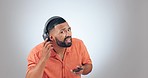 Listening, music and a man with a phone on a studio background for radio, streaming or fun. Happy, hear and a person with a mobile and attention with sound or audio for entertainment on headphones