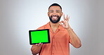 Tablet, green screen and man okay, yes and success hands for social media app or advertising in studio. Face of person on digital mockup and emoji subscription, tracking marker and a white background