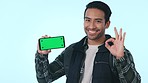 Happy asian man, phone and pointing to green screen or mockup in advertising against a studio background. Male person or tourist show OK, like or yes sign for perfect mobile smartphone app or display