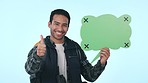 Happy asian man, speech bubble and pointing with thumbs up in advertising against a studio background. Male person smile with shape, OK or like and yes sign in social media or feedback on mockup