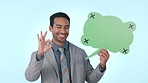 Business man, speech bubble and sign in studio, ok emoji or icon for review with mockup space by blue background. Entrepreneur, paper poster or billboard in portrait, quote or feedback with promotion