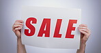 Sale, sign and hands with a poster, promotion and announcement of discount in studio with white background. Retail, shopping and person advertising with news, banner and deal for commercial savings