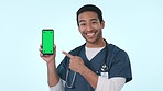 Asian man, doctor and pointing to phone on green screen or mockup in advertising against a studio background. Portrait of happy male person or nurse show mobile smartphone, healthcare app or display